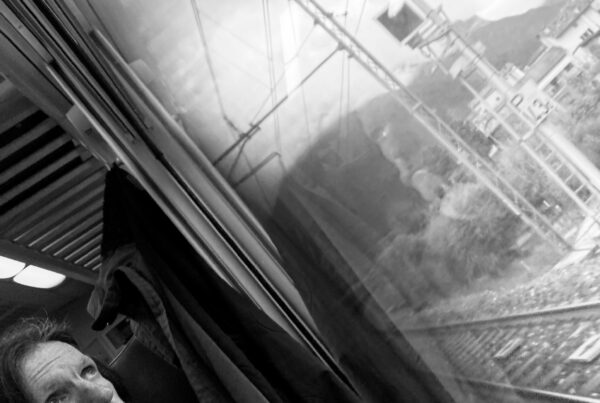 Man looking out of a train window as it speeds through the countryside.