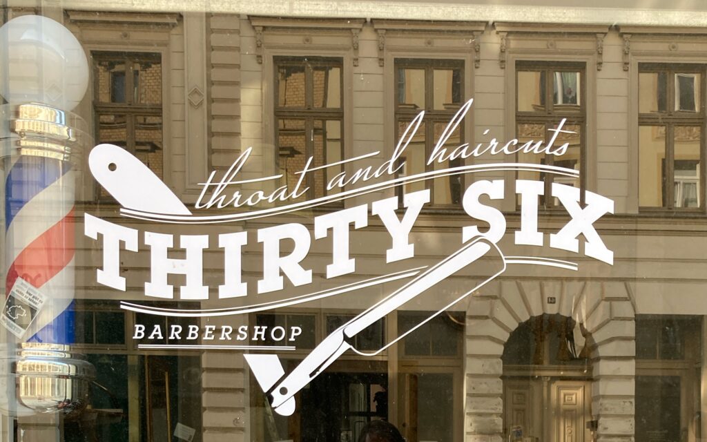 A shop sign that reads: "Thirty Six Barbershop. Throat and haircuts."
