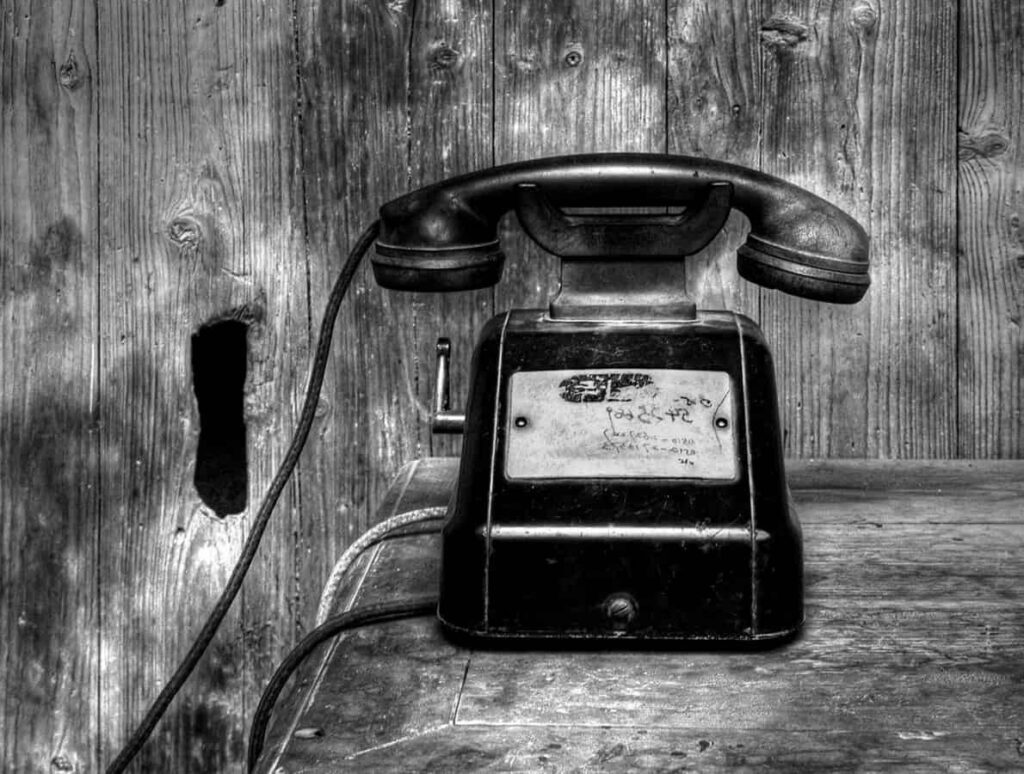 Black and white photo of an old phone with a handset resting on its horizontal cradle.