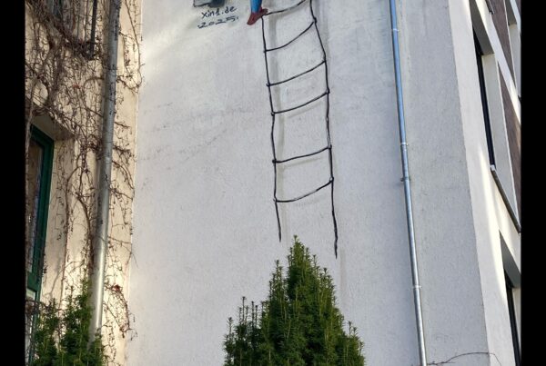 Image of street art on the side of a building in Leipzig. A woman leans down over a balcony and holds the hand and head of a man climbing up a rope ladder. She's wearing a yellow dress, he, a red tunic, blue tights, and red shoes. Both their costumes look late medieval.