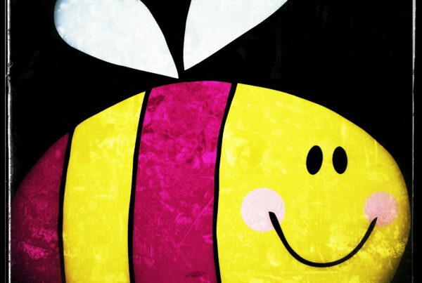 A picture of a cartoon, egg-shaped bee with purple-magenta stripes on its yellow body. It has two black dots for eyes, a big, smiling mouth, and rosy pink cheeks. It's borne aloft on two tiny white wings.